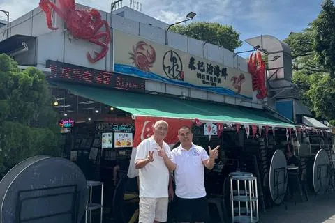 泉记海鲜煮炒老板林金祥（左）和儿子林俊豪，自10年前就与不同慈善机构合作送餐给弱势群体。（受访者提供）
