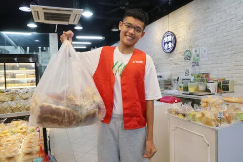 卓育玄晚上约9时到即将打烊的面包店领取面包，再送往指定受惠机构或配送中心。（蔡振鸿摄）