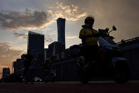 今年7月6日，北京中央商务区夕阳下，一名外卖员骑车经过中信大厦。（路透社档案照片）