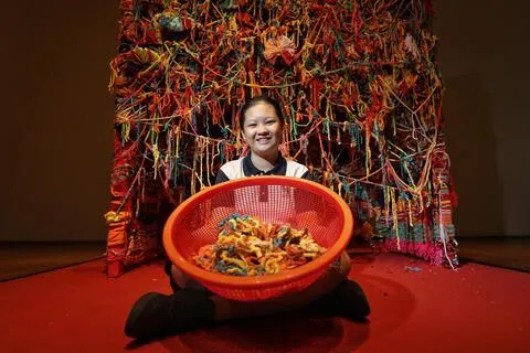 圣升明径学校与国家美术馆联合举办第8届年度艺术展“绽放”，首次参展的中二学生李婕宁在创作装置作品《我们的交织》过程中克服社交恐惧、主动协助同伴。作品利用缤纷毛线与回收布料搭建开放式装置，邀请公众共同编织，展现出学生重塑自信、勇于表达的蜕变历程。（何炳耀摄）