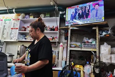 台湾舆论正关注中美元首峰会对台湾带来的影响。图为台北一名女子星期四（9月24日）在餐馆内工作，店内电视正播放美国总统特朗普迎接中国大陆国家主席习近平访美的新闻画面。（法新社）