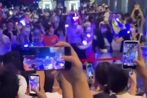 围绕时代峰峻的风波连日来持续发酵，图为一群人聚集在重庆长江国际大厦楼下，举起手机等候练习生进入公司。（互联网）