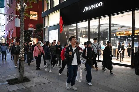日本官方数据显示，8月访日中国大陆游客锐减近六成，连续九个月同比下滑。图为一个中国游客团去年11月在东京途经资生堂美容店。（法新社）