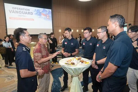 律政部长兼内政部第二部长唐振辉（左二）星期六在招待会上，与参与尼泊尔支援救灾行动的内政团队人员交流。（李冠卫摄）