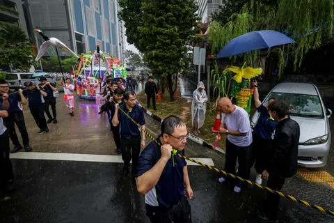 约500人为昇菘嫲黄宝来送殡，有人撑伞，有人披着雨衣，在雨中缓缓前行。（叶振忠摄）