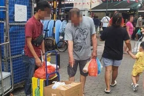 一名路过的公众，疑似正向身穿深红色衣的男子询问有关他售卖的咖喱角。（取自STOMP）