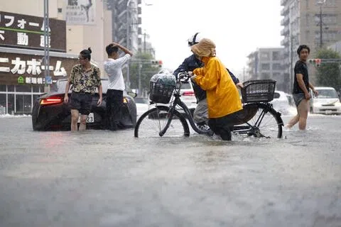 名古屋周二的每小时降雨量达104.5毫米，创下当地自1980年开始观测以来的最高纪录。图为当地居民周二涉水经过一条道路，也有汽车抛锚动弹不得。（路透社）