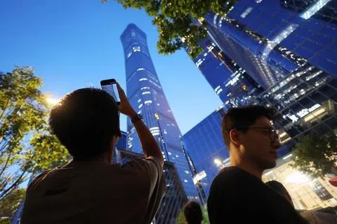 中国北京6月26日傍晚发生轻型飞机撞击中信大厦事件，引发首都卫戍失灵与社会治理风险等众多质疑。图为事件发生后，一名男子在北京街头用手机拍摄中信大厦。（路透社）