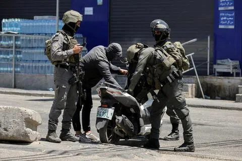 8月6日，在以色列占领的约旦河西岸的一处难民营，几名以色列士兵突击检查一名巴勒斯坦人的电单车。（路透社）