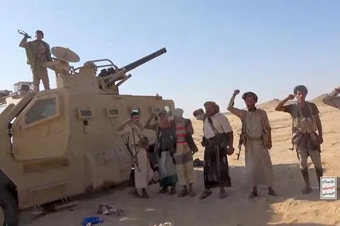 也门胡塞武装9月15日发布的视频截图，显示胡塞武装人员站在一辆缴获的军事车辆旁。（路透社）