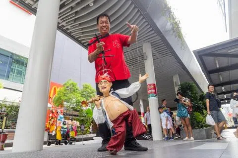 平日中午，在大巴窑市镇中心的街道上，从事人偶艺术表演逾60年的温忠全顶着烈日，操控手中的人偶。（吴先邦摄）