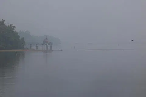 24-hr PSI in the north rises to 105 as at 9:30am. A viewing gallery at Sungai Buloh Wetland Reserves overlooking the causeway shoal with floating fish farm and the residential condominium from Johore Bahru barely visible due to the worsening haze condition.（SPH Media Limited）