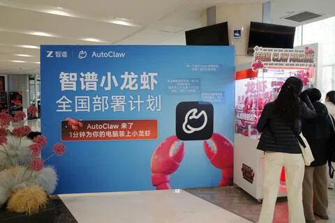 3月13日，在北京一栋办公楼内，人们站在一台装满龙虾造型毛绒玩具的抓娃娃机前。这是智谱开发的AI智能体OpenClaw本地版本AutoClaw的部署现场。（路透社）