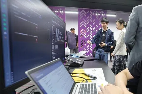 新加坡理工学院计算机系三年级学生邓宇翔（右二），向人力部代部长兼数码发展及新闻部高级政务部长刘洁敏（右一）讲解学院与新科工程联合设立的网络安全运营中心，如何协助中小企业监控网安威胁。（唐家鸿摄）