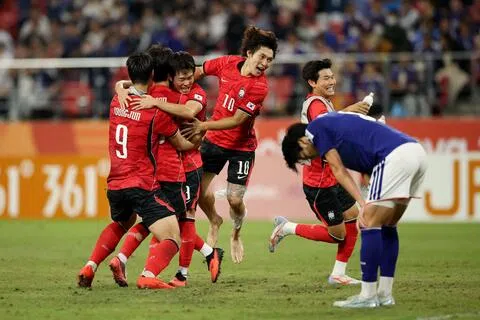 韩国球员（红衣）在赛后兴奋庆祝，一旁的日本球员（蓝衣）则相当失落。（路透社）