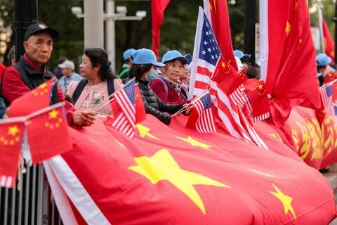 中国国家主席习近平抵美当天，民众当地时间9月23日聚集在华盛顿华尔道夫酒店附近，挥舞中美两国国旗，并在护栏前展开一面大型中国国旗。（路透社）