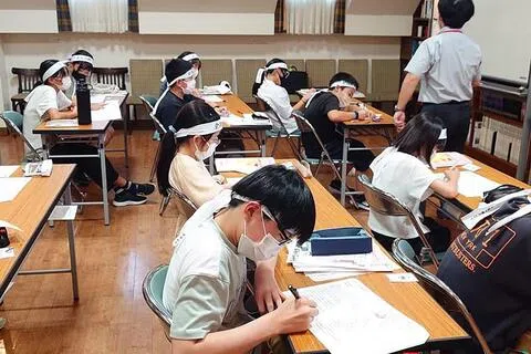 日本近来出现大量“魔鬼集训营”式的高压补习班，虽然收费不菲，但仍吸引许多家长为孩子报名。图为在其中一个补习班，孩子们上课时绑上“必胜”头巾，希望考入理想的学校。（互联网）