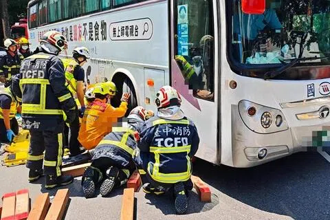 67岁新加坡籍女子在台湾台中旅游过马路时，遭一辆国光客运撞倒并卷入车底。救护人员到场急救。（自由时报）