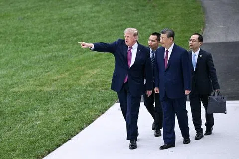 在中美两国领导人双边会晤结束后，美国总统特朗普（前排左）与中国国家主席习近平（前排右）在白宫南草坪上散步时，特朗普指着新建的直升机停机坪。（法新社）