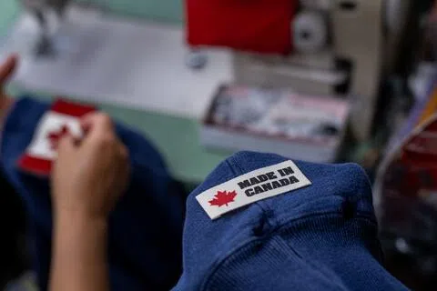 美国和加拿大之间的贸易战持续升级，图为9月2日，工人在安大略省的一家制衣厂，把写有“加拿大制造”字样的标签车缝在夹克领口内侧。（彭博社）