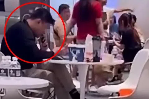 男子无视一旁的小孩，在商场举行的车展公然吸电子烟。（取自网络）