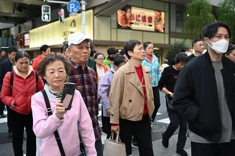 日本政府观光局星期三（8月19日）公布最新数据显示，今年前七个月，访日中国大陆游客数量同比下降56.3%。图为一组中国旅游团去年11月17日在日本东京银座购物区道路上行走。（法新社）