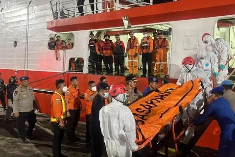 9月18日，身穿防护服的搜救人员运送此前寻获的Virgo Transport 8倾覆事件遇难者遗体。（路透社）