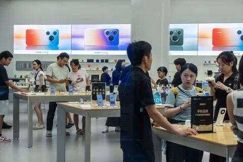 受存储晶片价格飙升影响，中国华为、小米和荣耀等多个手机品牌均上调部分机型售价。图为8月23日，海口国际免税城一家华为门店内的顾客在选购手机。（彭博社）