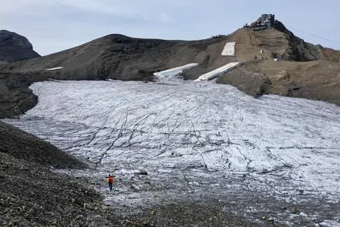 无人机的航拍画面显示，瑞士塞克斯鲁日冰川的大部分积雪已经融化，暴露出深褐色的土地。（路透社）