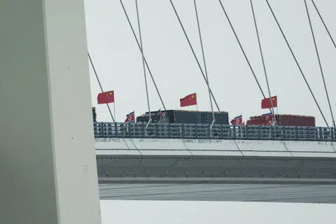 连接中国辽宁省丹东市与朝鲜平安北道新义州市的新鸭绿江大桥，星期四（10月15日）正式开通。当天，悬挂朝鲜国旗的卡车驶入新鸭绿江大桥的中国一侧。（路透社）