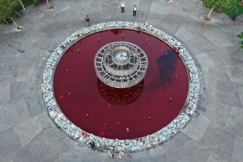 2026年10月7日，在以色列沿海城市特拉维夫，人们聚集在被注入红色染料的迪岑戈夫喷泉（Dizengoff Fountain）旁，以纪念哈马斯发动“10月7日”袭击三周年。（法新社）