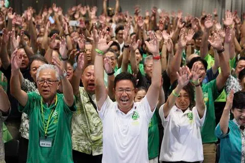 古谢玄太（中）星期天在媒体预测他在冲绳县知事选举中胜出后，与支持者一起庆祝。（法新社）