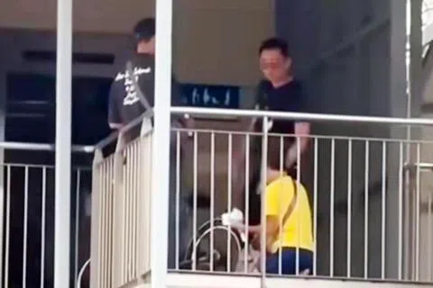 一名身穿黄色上衣的年长女子疑在天桥上违规骑行，被执法人员拦截后单膝下跪，貌似请求后者网开一面。（取自网络）