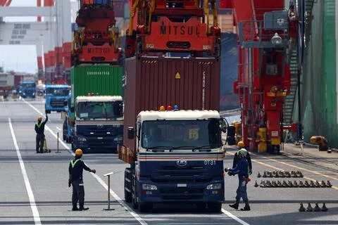 日本7月连续第三个月出现贸易逆差。图为8月20日，日本首都东京一个工业港口的工人将集装箱装载到货船上。（路透社）