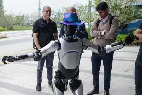 外国投资者4月20日在上海参观智元创新科技股份有限公司总部期间，与该公司研制的人形机器人互动。（路透社）