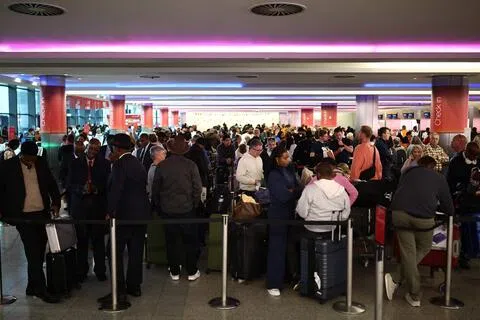 9月8日，在伦敦希思罗机场的3号航站楼，大量受航班延误影响的旅客拖着行李排队等候。（法新社）