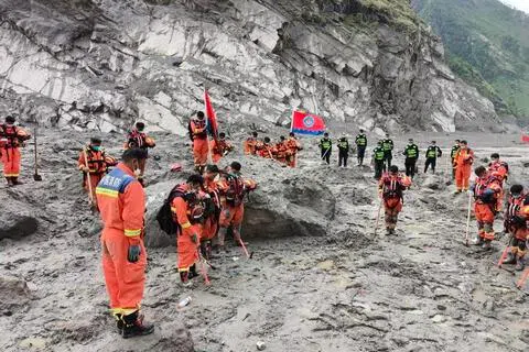西藏自治区星期二（9月1日）上午9时55分在日喀则市公安局吉隆口岸分局举行遇难者哀悼活动，泥石流灾害救援现场、道路抢通现场等同步举行，多方人员、地方干部群众等参与哀悼活动。图为救援人员在救灾最前沿的口岸区域默哀。（新华社）