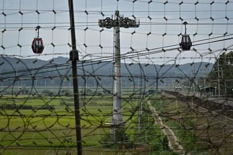 9月12日，在非军事区韩国一侧的坡州临津阁公园，游客乘坐和平缆车，飞越“平民控制区”上空。（法新社）