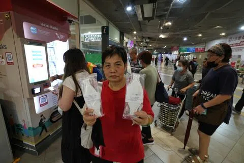不少民众到宏茂桥巴士转换站的自助领取机领N95口罩，居民林春英（69岁）在新捷运员工的协助下领了两个口罩。（梁麒麟摄）