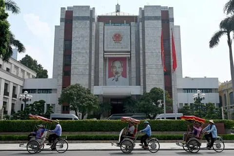河内三轮车夫行经河内的人民委员会大厦。越南当局近日逮捕三名男子，指控他们意图从柬埔寨非法入境越南发动“恐怖与破坏活动”。（法新社）
