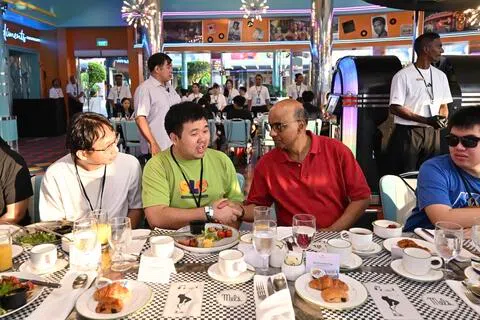 尚达曼总统（前排右二）于星期六在新加坡环球影城与29岁中等自闭症患者姚启扬（前排左二）及其他受益者交流。（圣淘沙名胜世界提供）