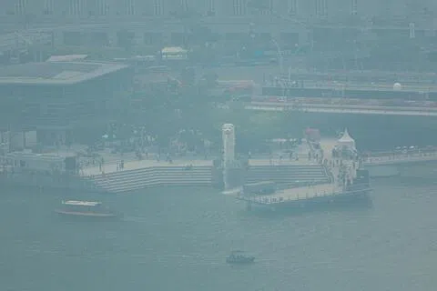 本地空气质量星期五恶化，《联合早报》摄影记者下午从新加坡摩天观景轮拍摄的画面显示，旅游地标鱼尾狮一带被烟霾笼罩，景物一片朦胧。（李冠卫摄）