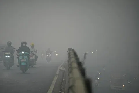 10月15日，在印尼南苏门答腊省巨港市，林火引发的有害烟霾遮天蔽日。大批佩戴防护口罩的电单车骑手顶着极差的能见度，穿行在当地繁忙的大桥上。（路透社）