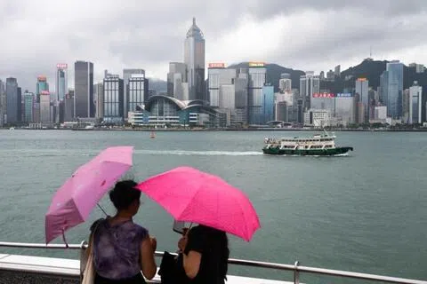 7月30日，两名游客撑伞在香港尖沙咀海滨长廊眺望维多利亚港。（彭博社）