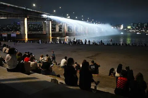 韩国民众7月28日在首尔汉江盘浦大桥观赏“月光彩虹喷泉”。（法新社）
