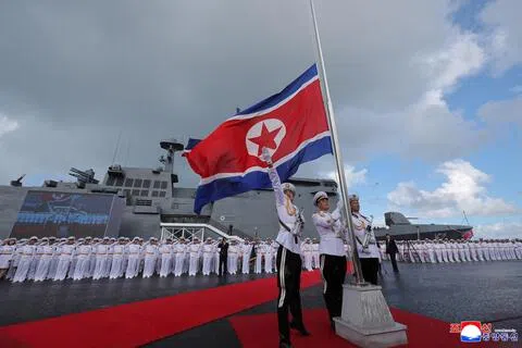 9月6日，在朝鲜驱逐舰姜健号服役仪式上，军方人员升起朝鲜国旗。（路透社档案照片）