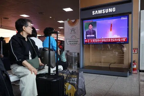 韩国民众星期一（10月12日）在首尔一个火车站，观看电视报道有关朝鲜向东海岸附近海域发射多枚弹道导弹的新闻。（路透社）