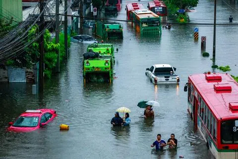 曼谷遭豪雨侵袭，多条街道积水成灾，民众只能涉水通行。（路透社）