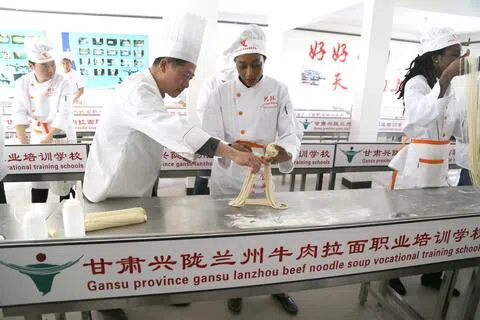 甘肃兴陇职业培训学校创始人梁顺俭说，目前拉面人才需求量大，拉面师薪资也水涨船高。图为一名海外学员在教师的指导下学习制作拉面。（受访者提供）