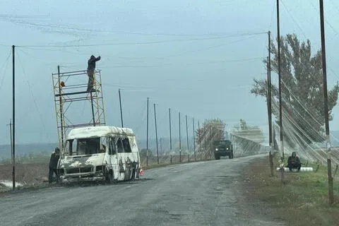 乌克兰工人周三在乌东前线城市克拉马托尔斯克（Kramatorsk）附近的一条公路安装防无人机网，以防范俄罗斯无人机袭击。（路透社）
